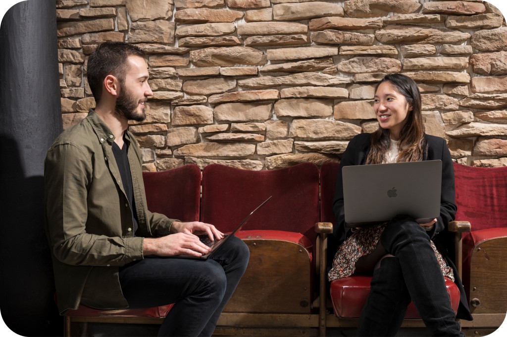 Two of Afelio’s employees discussing with their respective laptops on their laps.